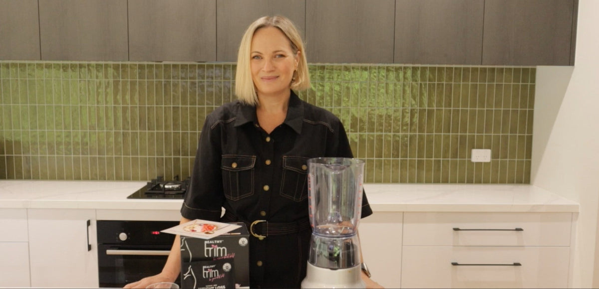 Lady standing in front of a Healthy Trim box ready to make a recipe with a blender.
